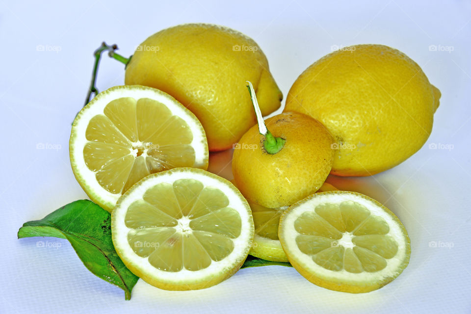 Halved and full lemon against white background