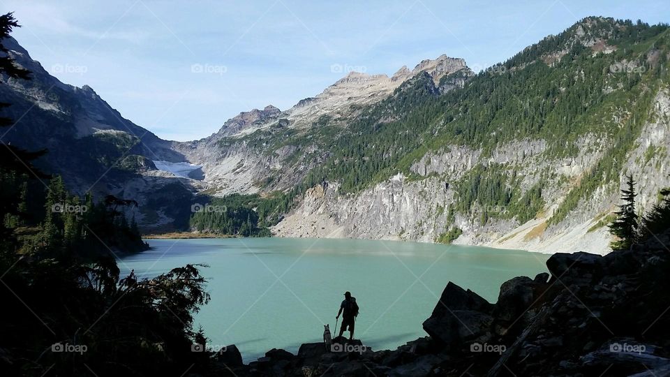 Hiker with Dog View Mountain L. Man hiking with Dog looking over turquoise Blanca Lake in the Cascade Mountains