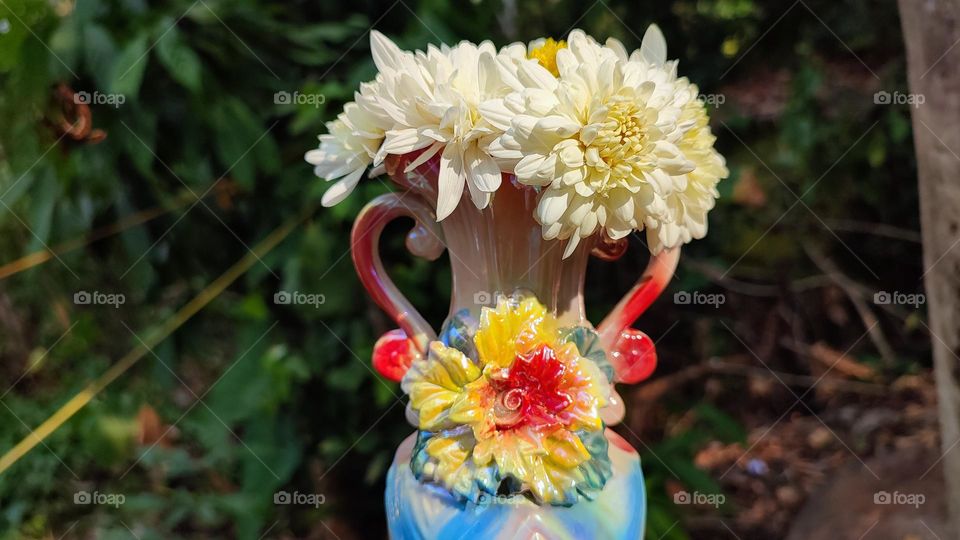 Beautiful white flowers in a colourful flowerpot with a flower sculpture