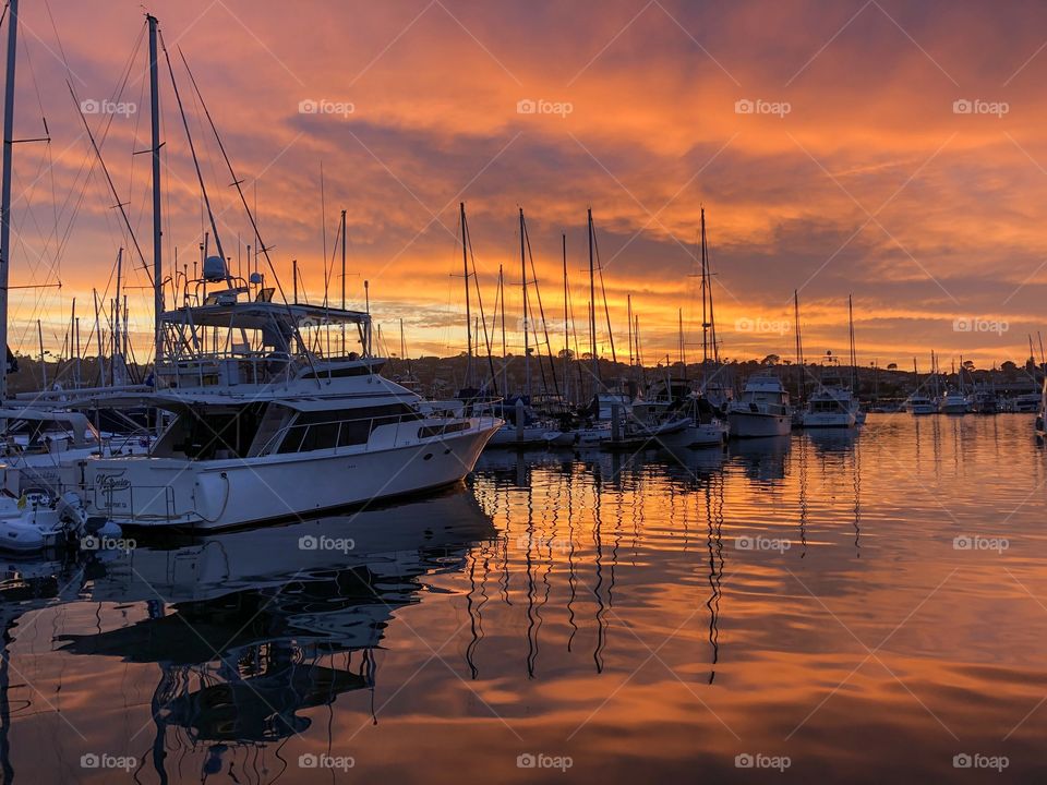 Sunset in marina with sailboat masts reflections on water