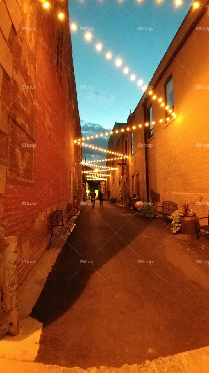 A single string of lights bounce colorfully off the alley walls on a early evening stroll.