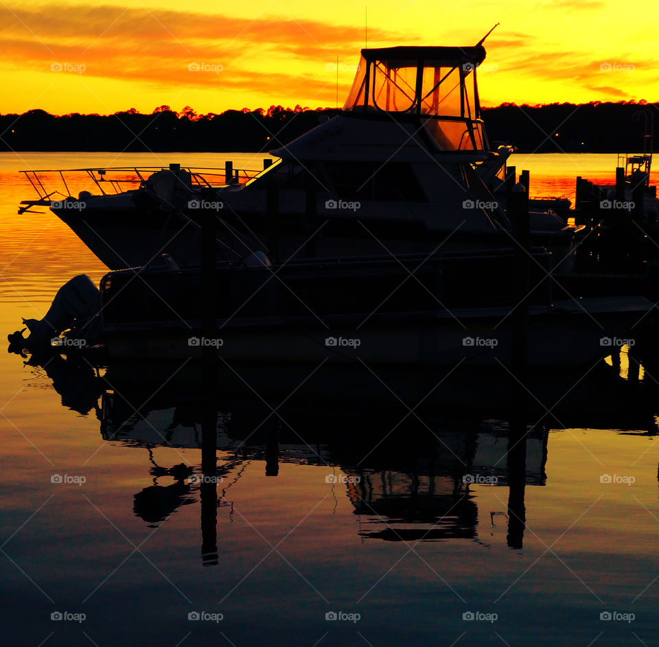 Watercraft docked in the bayou reflecting themselves in the brilliant sunset!