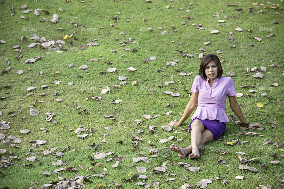 Portrait Asean woman sitting on the lawn in a park.