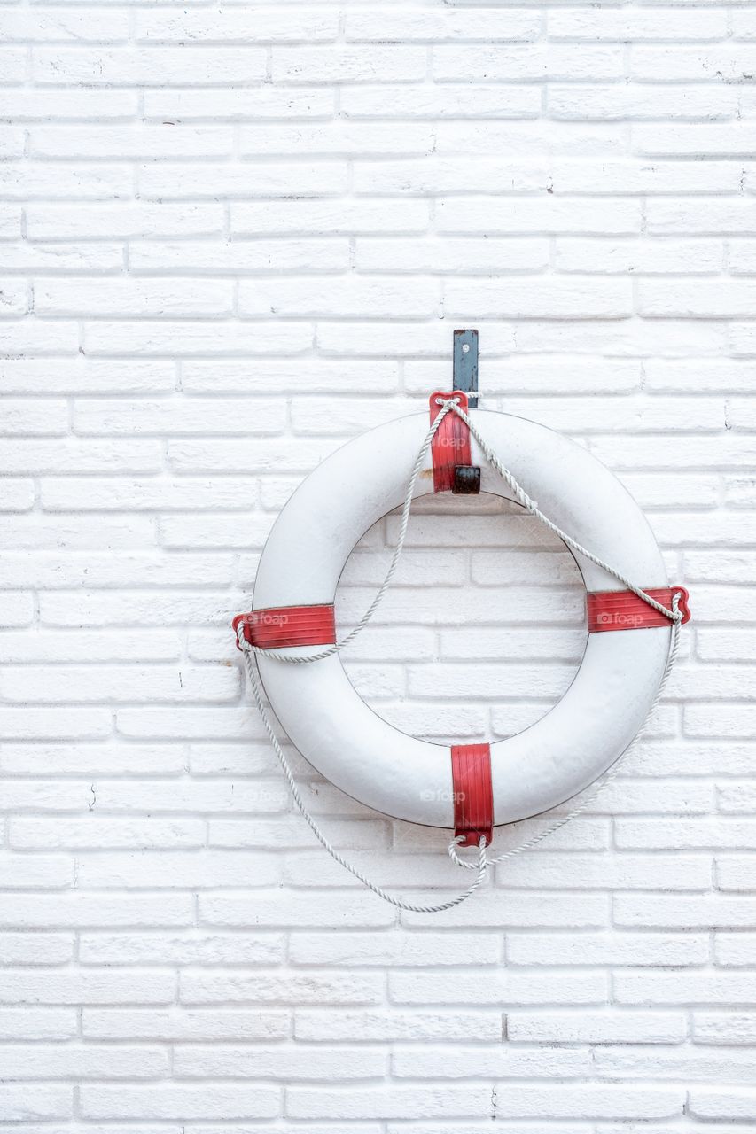 White lifebuoy on a white brick wall