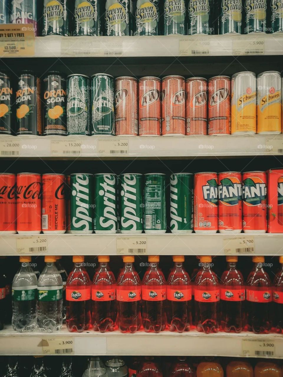 Portrait of a shelf in a shop filled with various types of soft drinks in cans and bottles