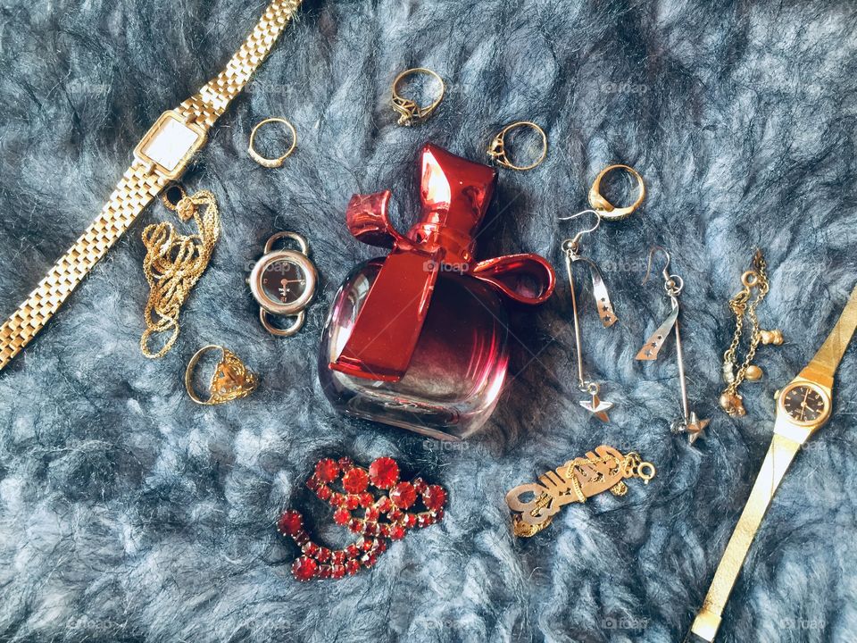 Red perfume bottle in the middle between some accessories 