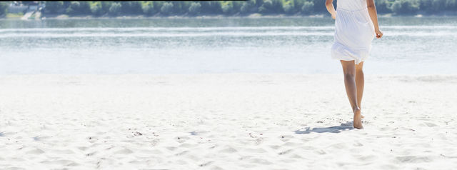 woman running on beach. woman in white dress running across sandy beach