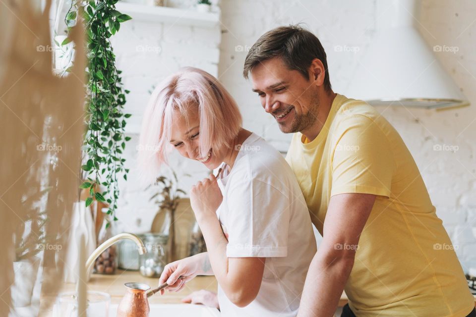 Young beautiful couple happy family having fun and wash dishes in bright kitchen at home