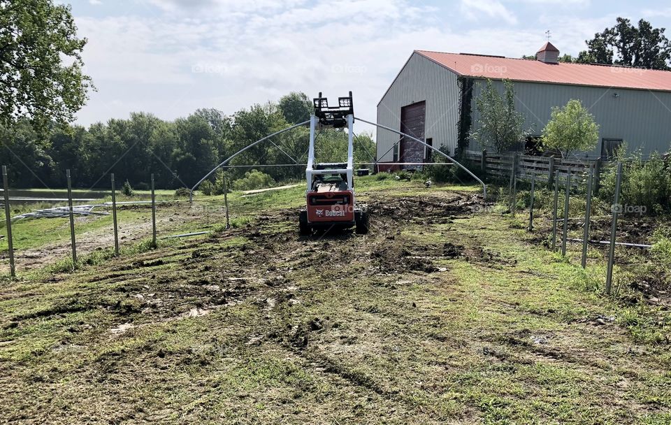 High Tunnel Construction Project, Bobcat, truss, bough, dirt, steel, tubing, pipe, equipment, machine, barn, greenhouse, grass, weeds, posts