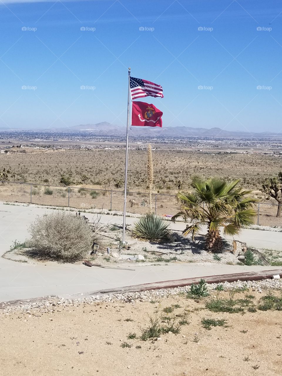 Magnificent United States Of the America American flag and United States Marine Militry Flag outside a small farm in the desert in California.