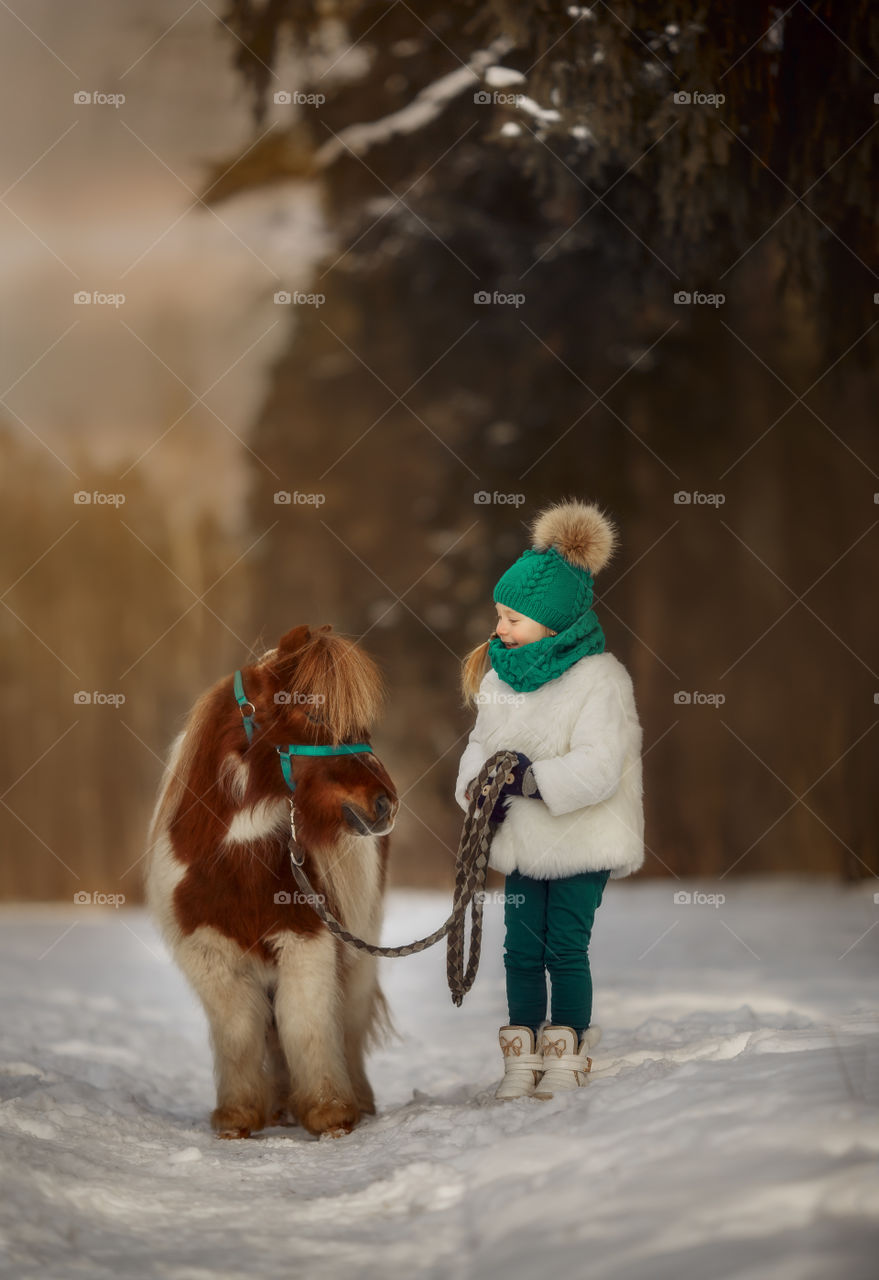 Little girl with pony at early spring day