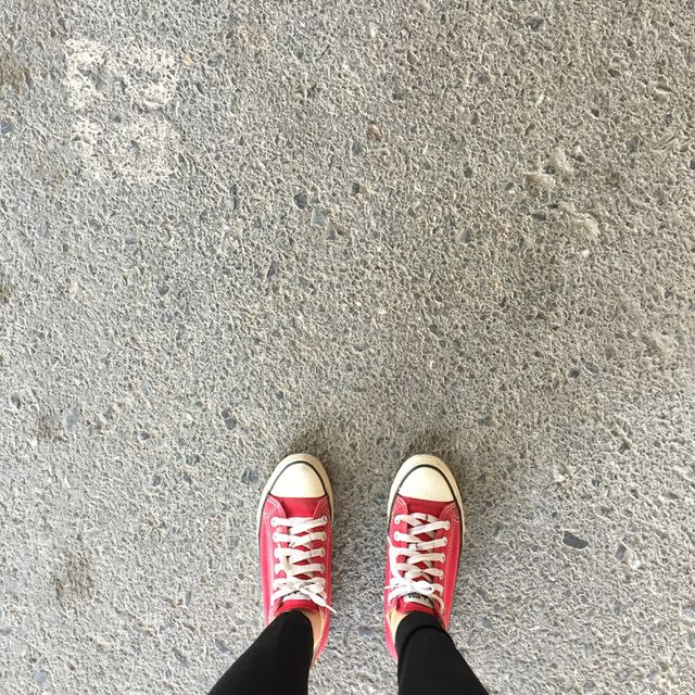 Red Sneakers Shoes Walking On Dirty Concrete Top View , Canvas Shoes Walking On Concrete Great For Any Use.