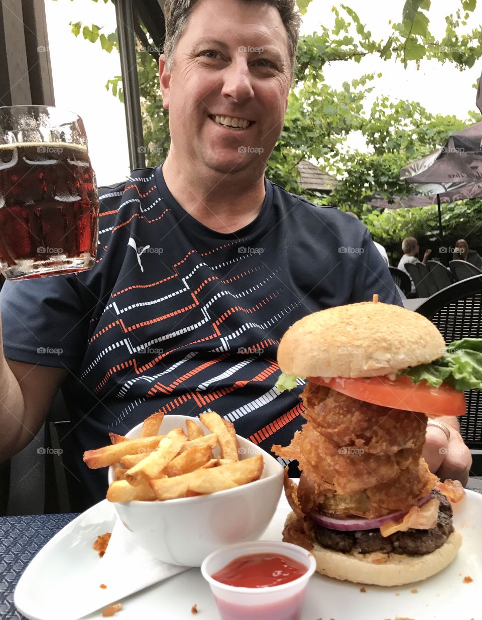 Man eats huge burger, fries and beer