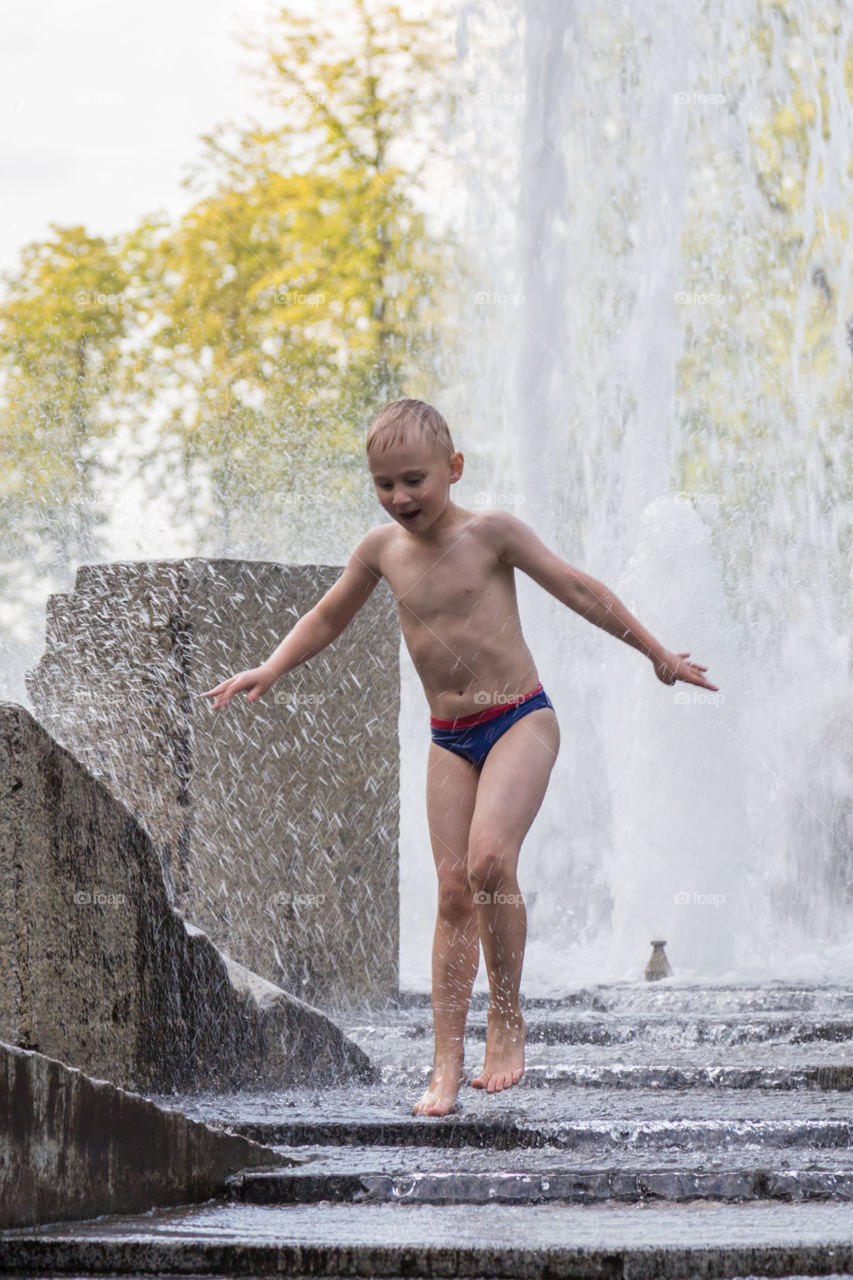 A boy is playing in a fountain