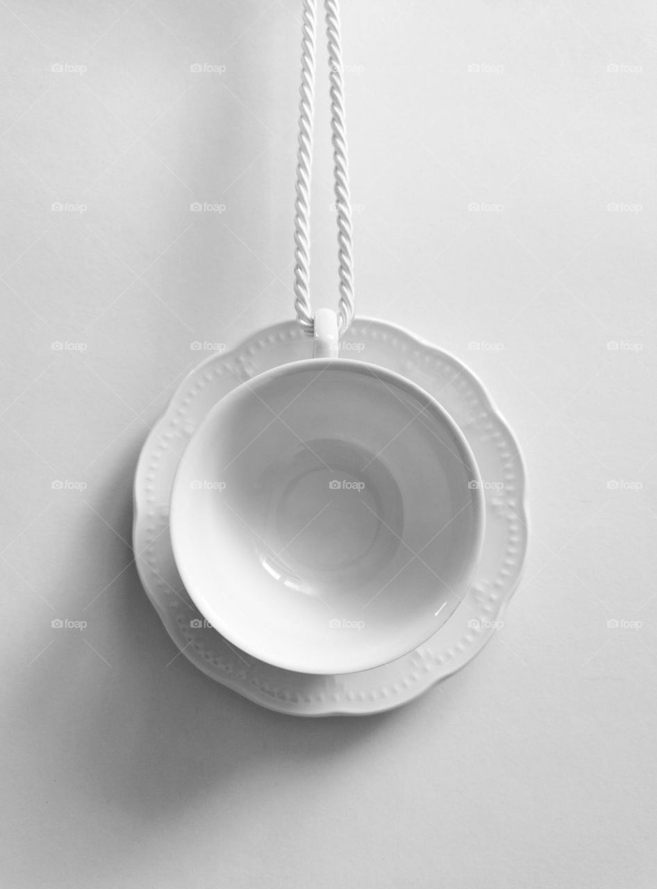 Minimal photo of white coffee cup hanging as a pendand against white wall