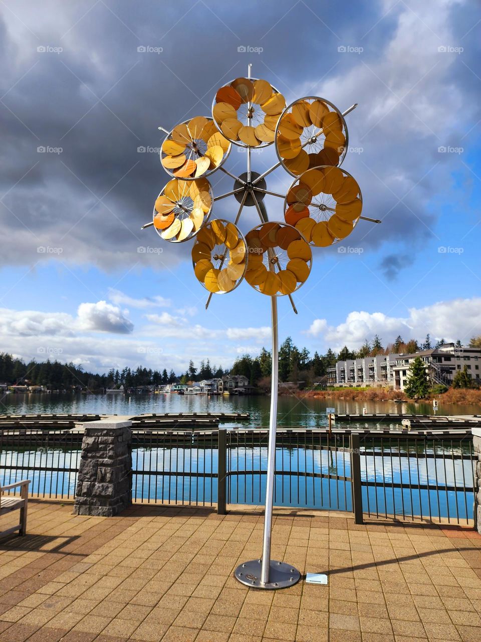 A huge yellow set of circular paddles is arranged to look like a big wildflower in a lakefront downtown area