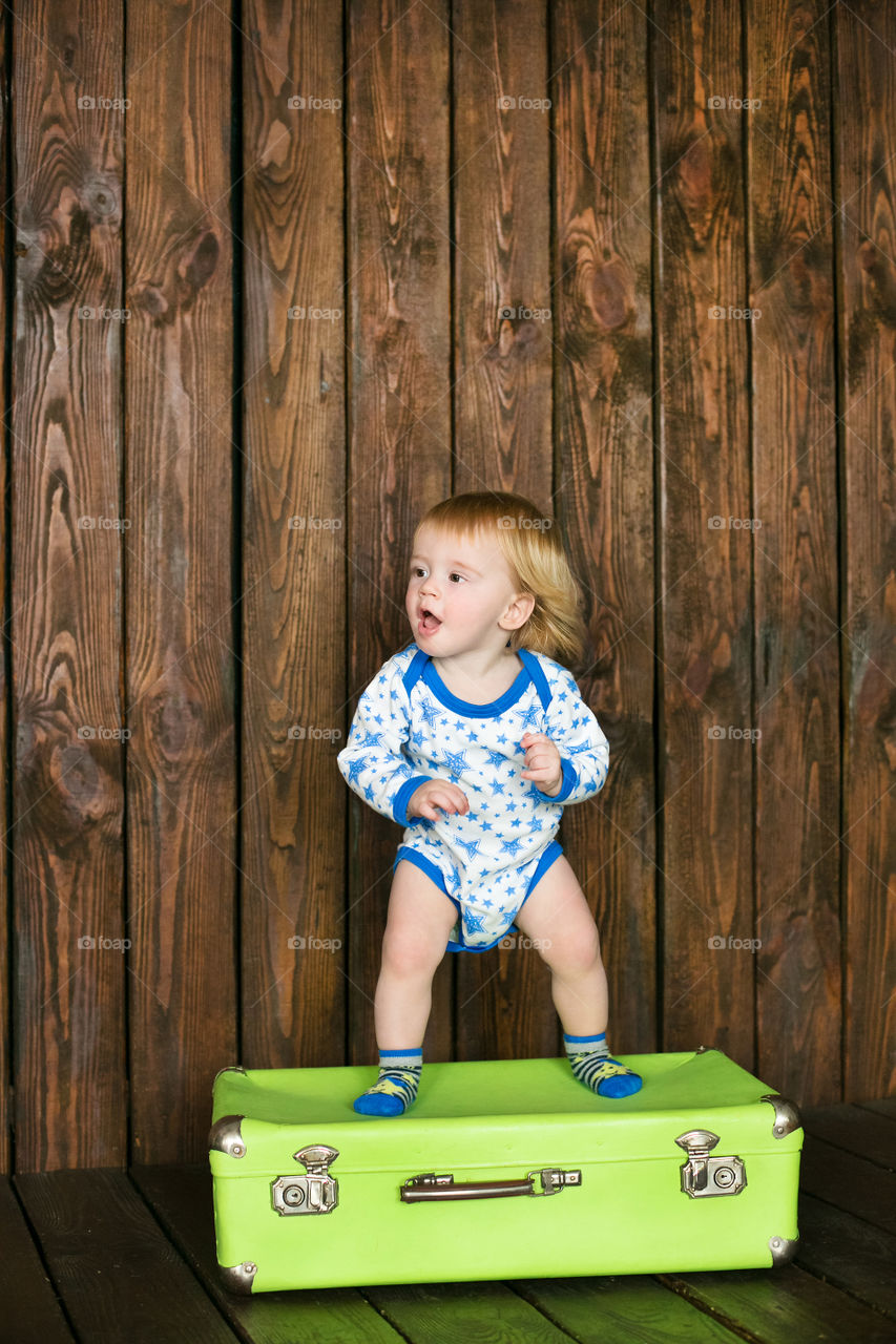 Cute little boy standing in metallic suitcase