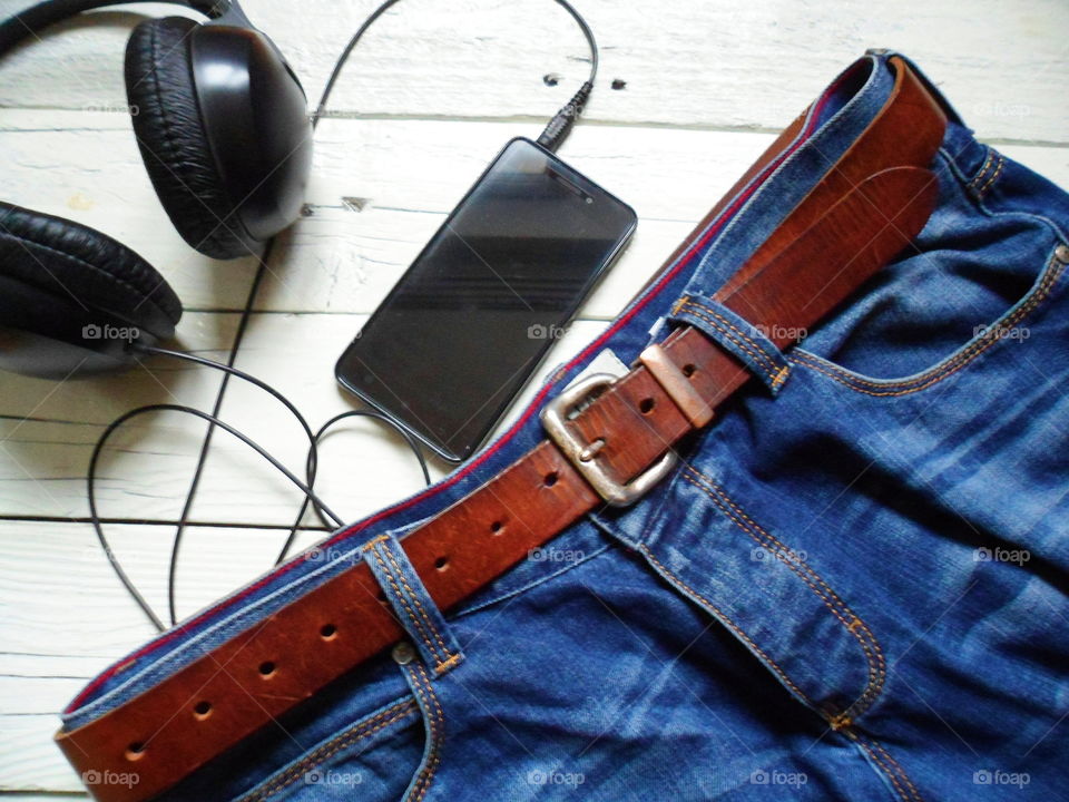 blue jeans with leather belt, smartphone and headphones