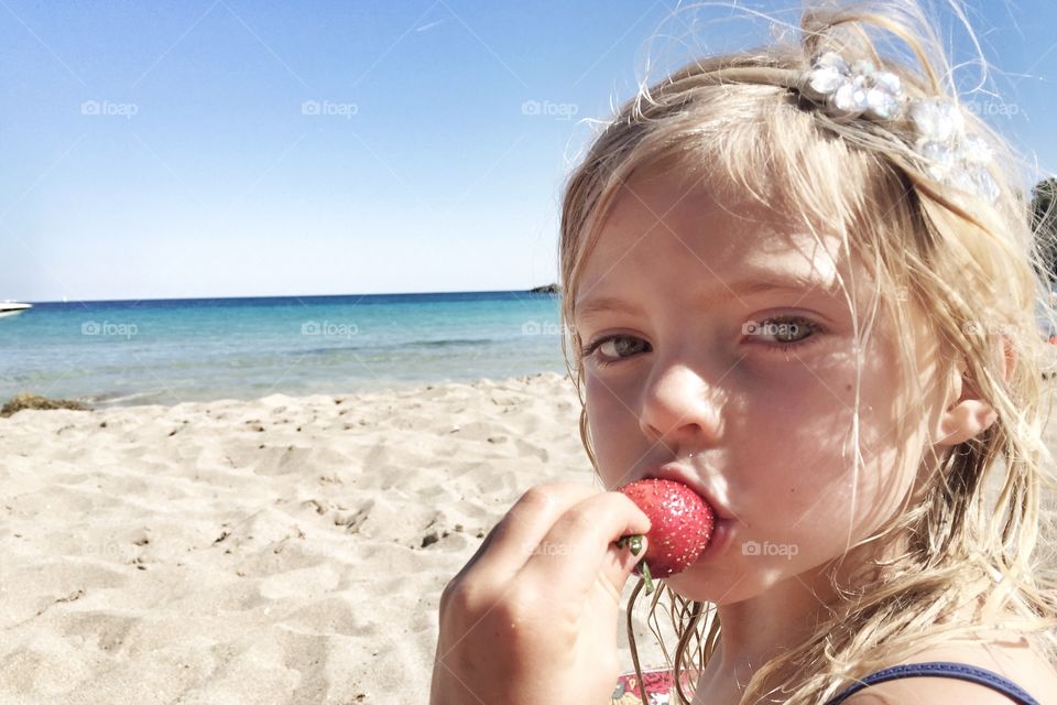 Close-up of a girl eating strawberry at beach