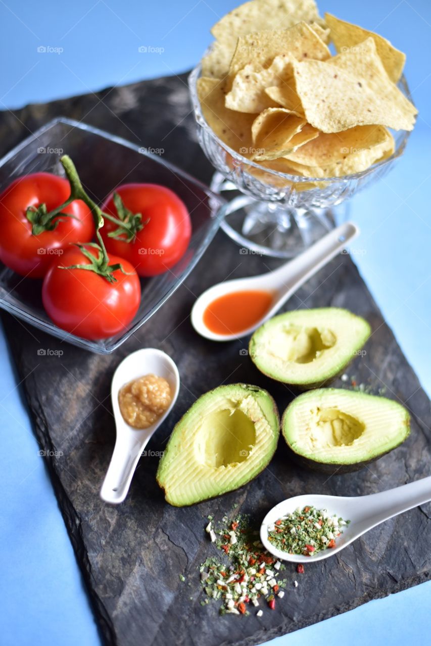 Healthy vegetables for spring time cooking at home. Tomatoes, avocado and spices for the perfect guacamole.