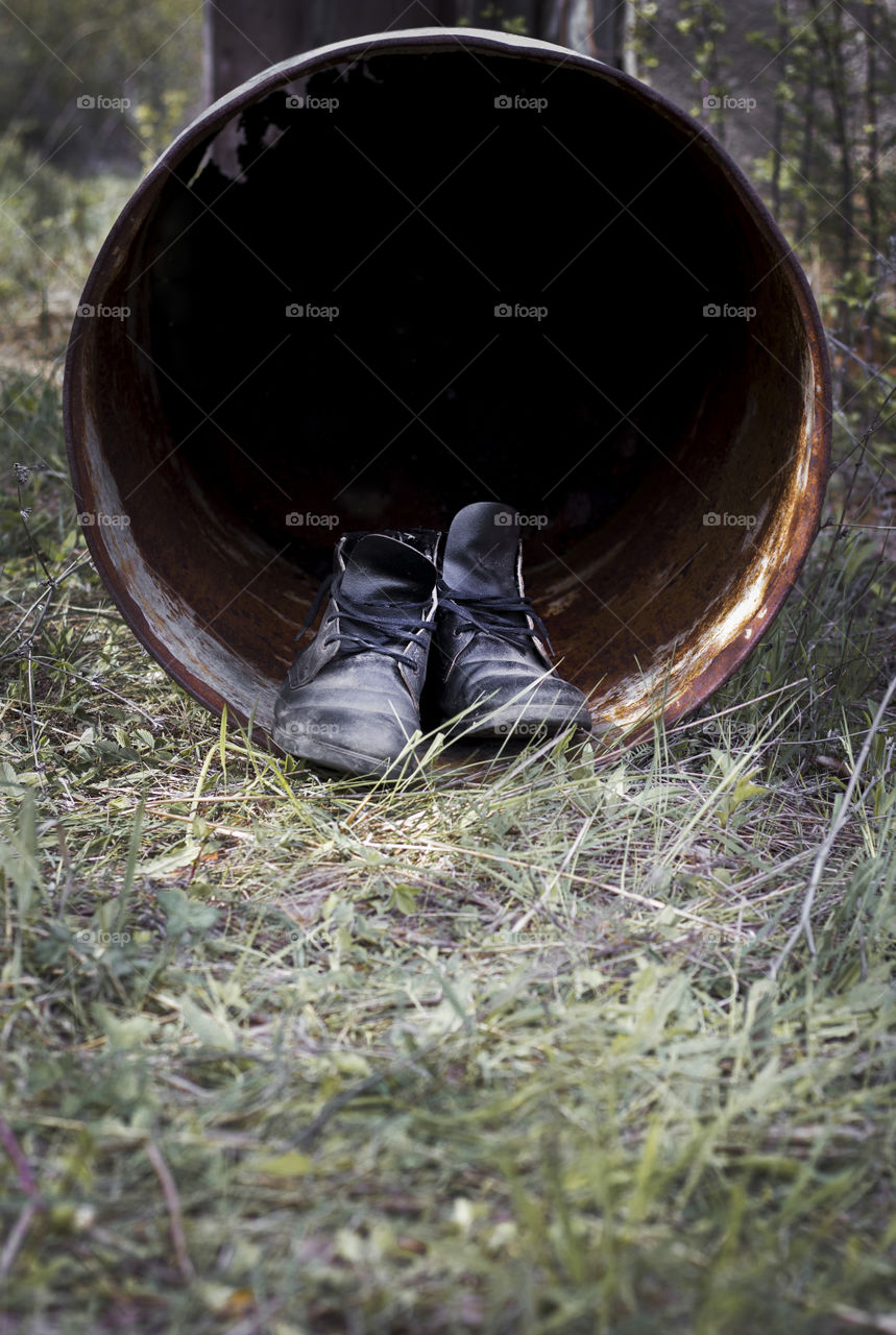 Black hole in metal barrel tunnel and old shoes outdoor