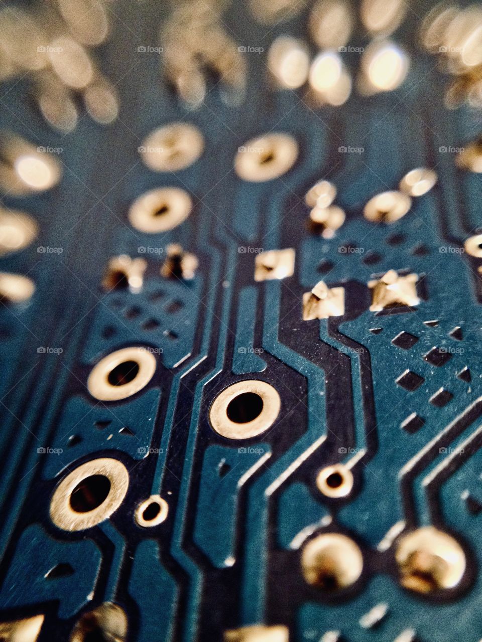 Closeup of a blue printed circuit board with bokeh focus fading into the distance.