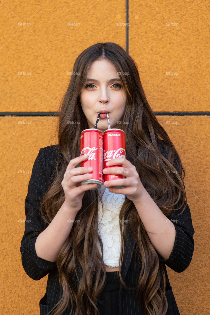 Young girl enjoying Coca-Cola. Two cans in hands