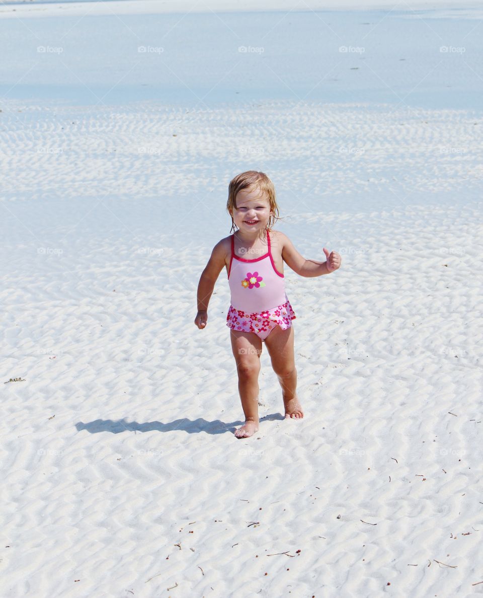 Cute girl walking on sandy beach
