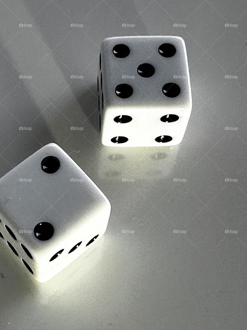 iPhone 14 Pro close up of dice faces showing seven on white plastic background with flashlight highlight/shadows