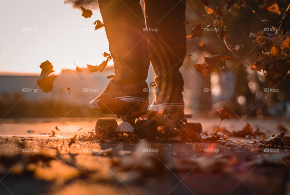 Boy riding a skate through leaves.