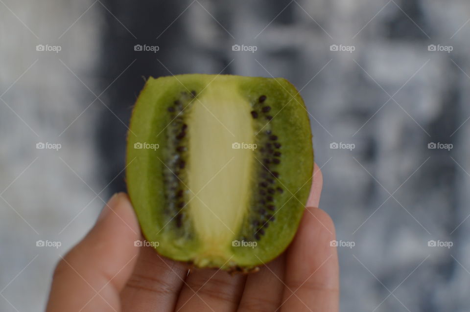 Close-up of hand holding kiwi fruit