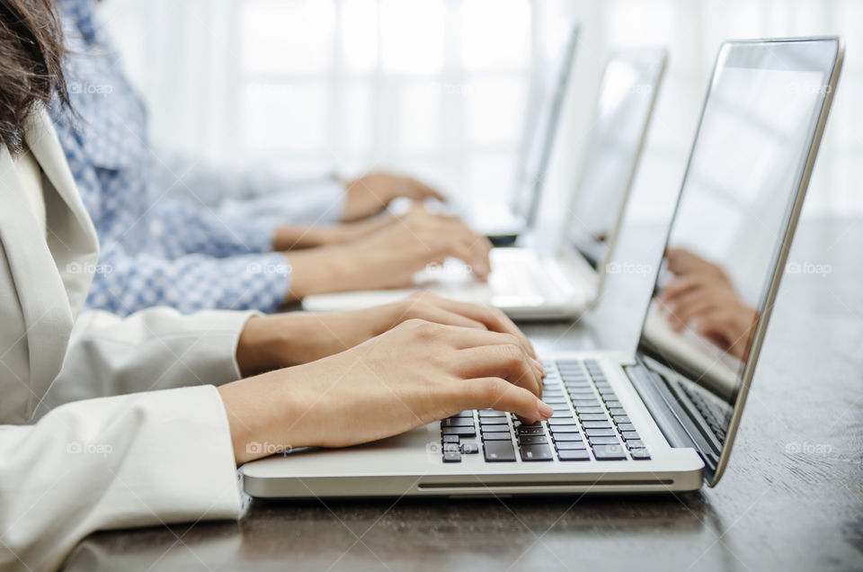 Business people sitting in row using laptop on desk