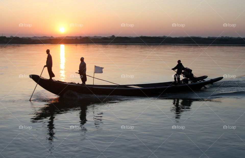 The sun rises over a boat making its way along the Irrawady River in Myanmar