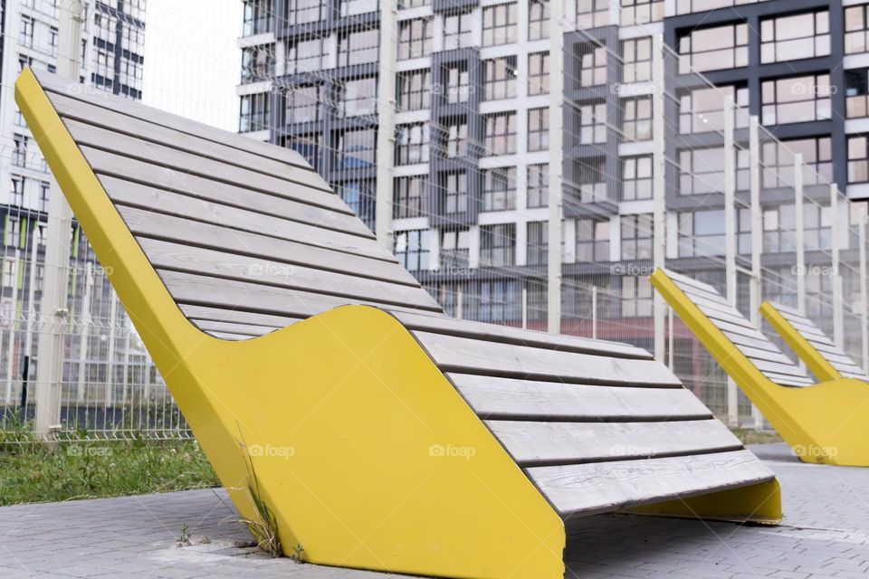 Yellow, wooden benches on the street of a modern city