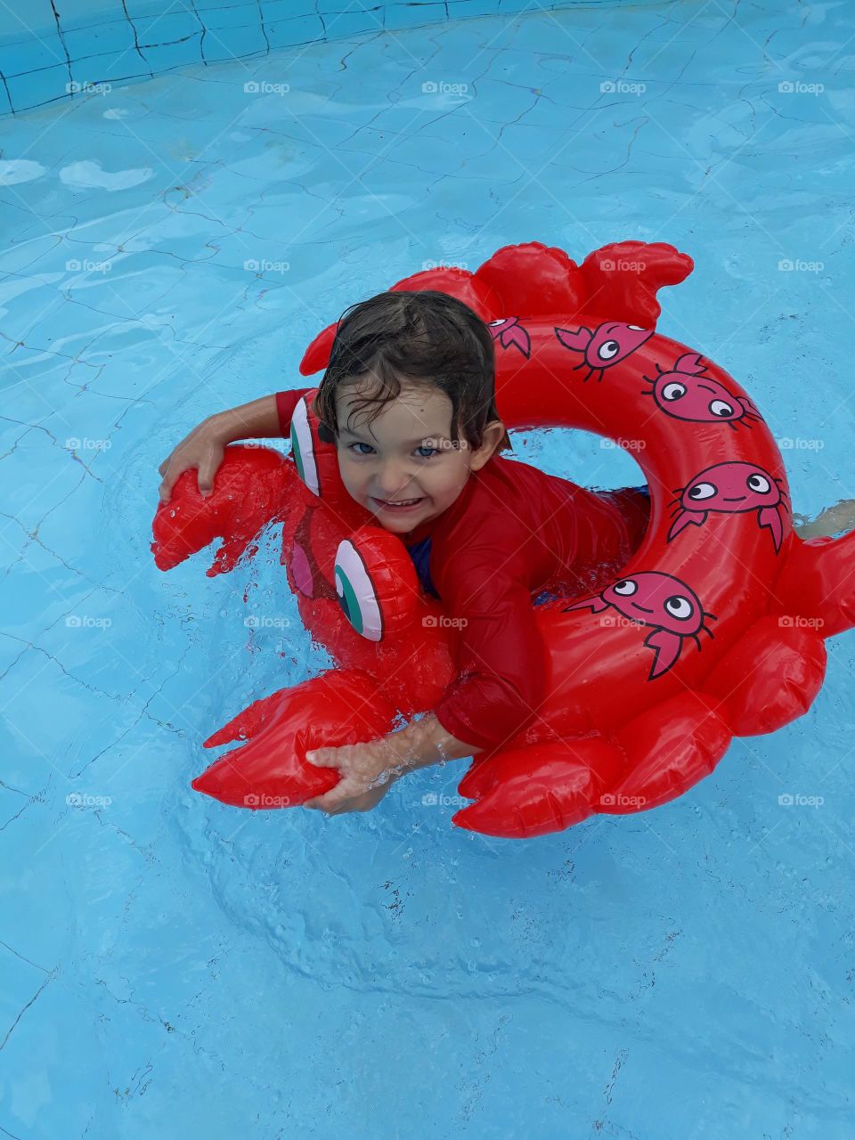child swimming in pool with buoy and red blouse