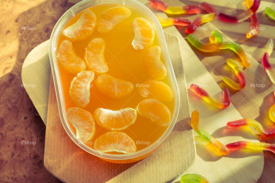 Delicious orange jelly with tangerine slices in a container and jelly worms.