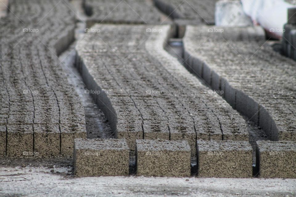 rows of molded cinder blocks still raw products lie in a row
