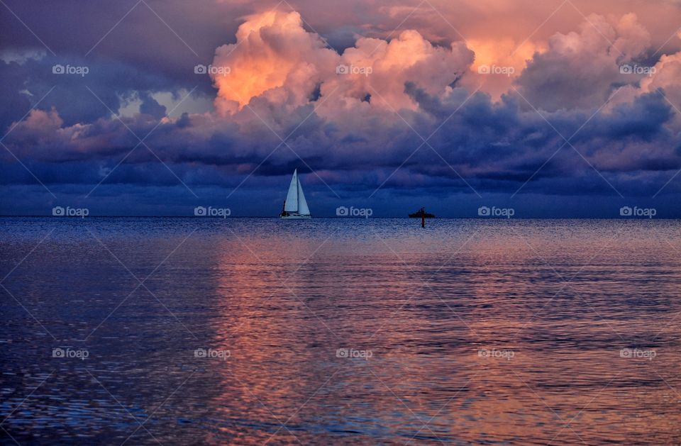 white sailboat at the dramatic cloudy sky during summer sunset over the baltic sea in poland