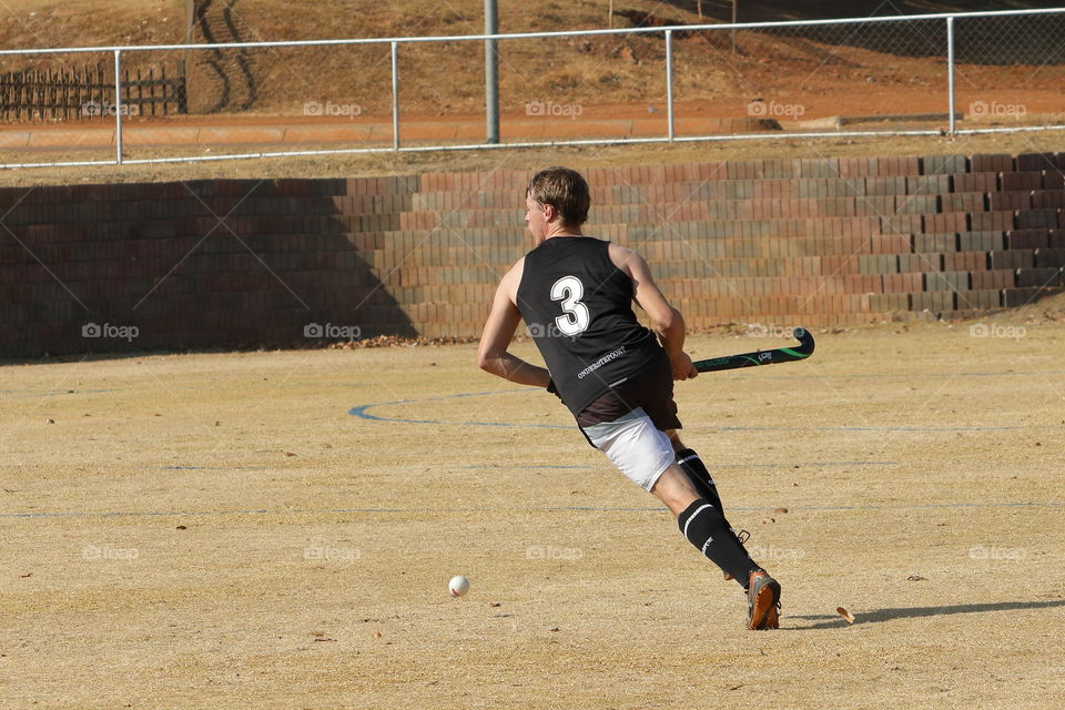 Young man running with the ball during a field hockey game