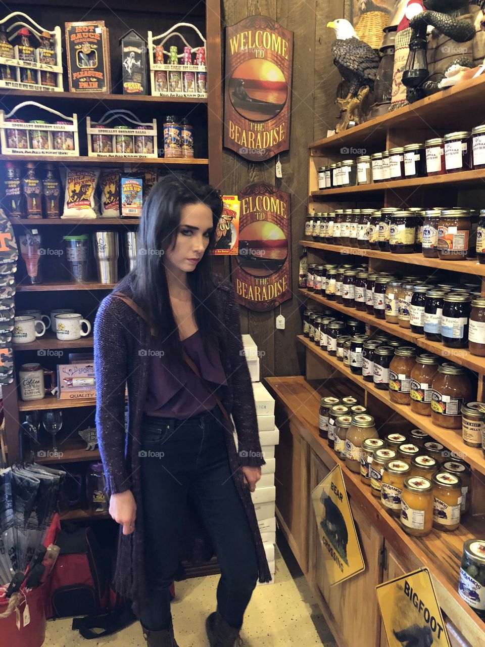Young pretty woman  in a country store where there are jams and jellies all lined up. 
