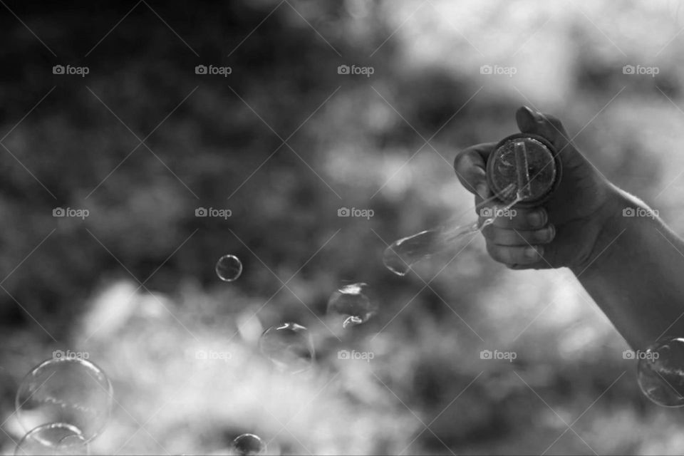 Black and white photo of a child's hand playing with soap bubbles