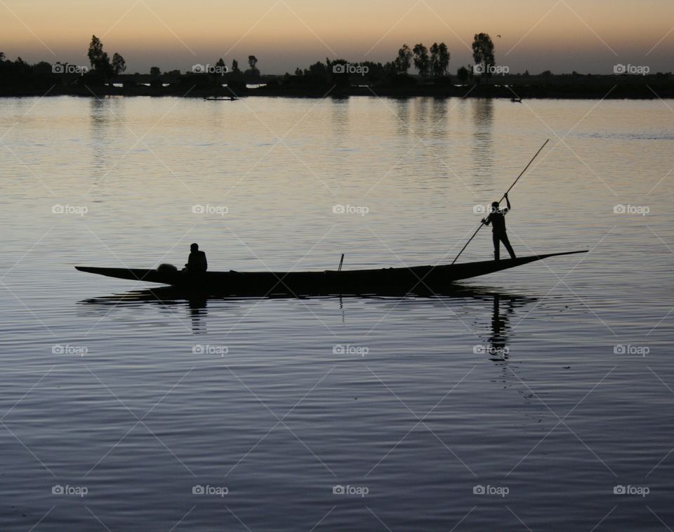 A boat makes its way along the Bani River in Mopti, Mali at dusk