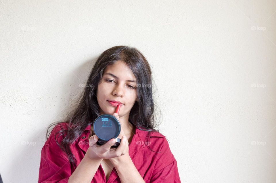 Beautiful woman applying lipstick on her lips.