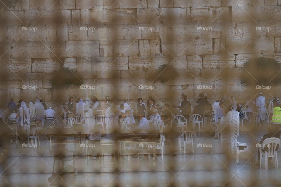 people praying in western wall of Jerusalem of Israel, as seen from the fence