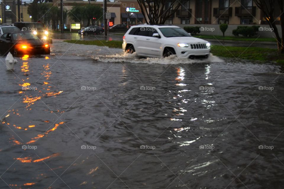 Two vehicles trying to get through flooded street, deep water