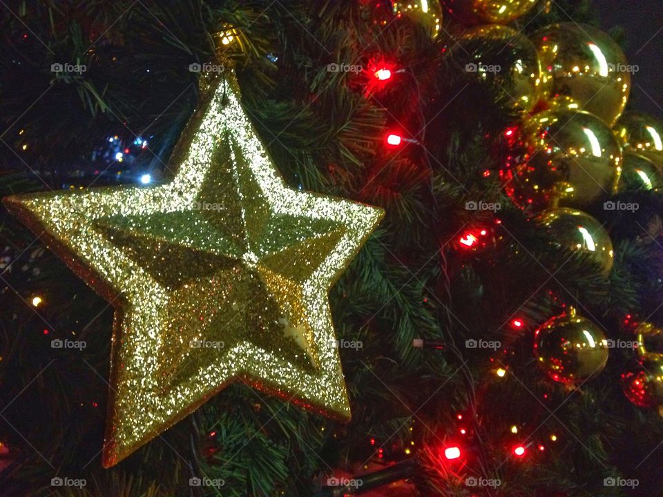 Gold plastic star, balls, red lights garland and other Christmas decorations on artificial fir tree in Moscow, Russia