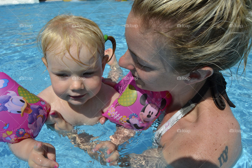 Mom and her two year old doughter playing and swimming in the pool on their family holiday in Turkey.