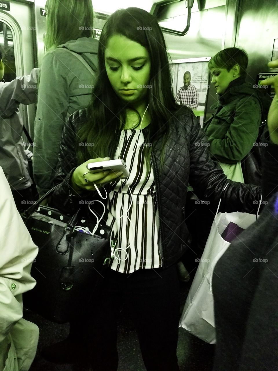 Girl Riding Subway in NYC Looking at her Phone. Green Filter.