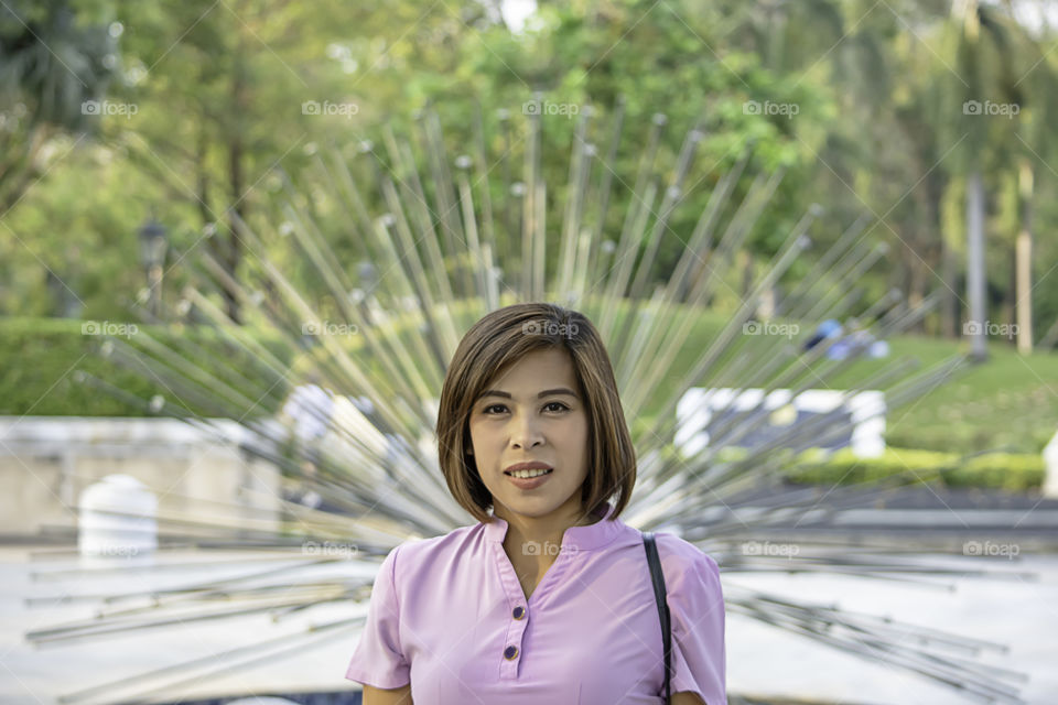 Portrait of Asean Women with short hair brown Background Trees and grass that are blurry.