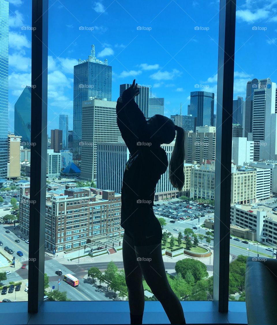 Volleyball girl in silhouette in front of downtown skyline 